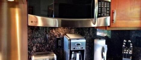 A kitchen with stainless steel appliances including a microwave, toaster, and coffee maker.