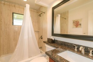 Une salle de bain avec une douche, un grand miroir et deux lavabos.