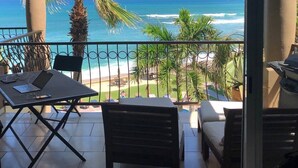 A balcony with a view of the ocean, a table with a laptop, and chairs. - BRAND NEW Remodel & BEST Oceanfront BEACH/SURF Location In Cabo!!! (San José del Cabo)