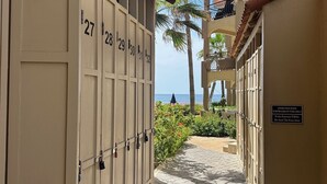 A corridor with numbered doors leading to rooms, palm trees, and a view of the sea. - BRAND NEW Remodel & BEST Oceanfront BEACH/SURF Location In Cabo!!! (San José del Cabo)