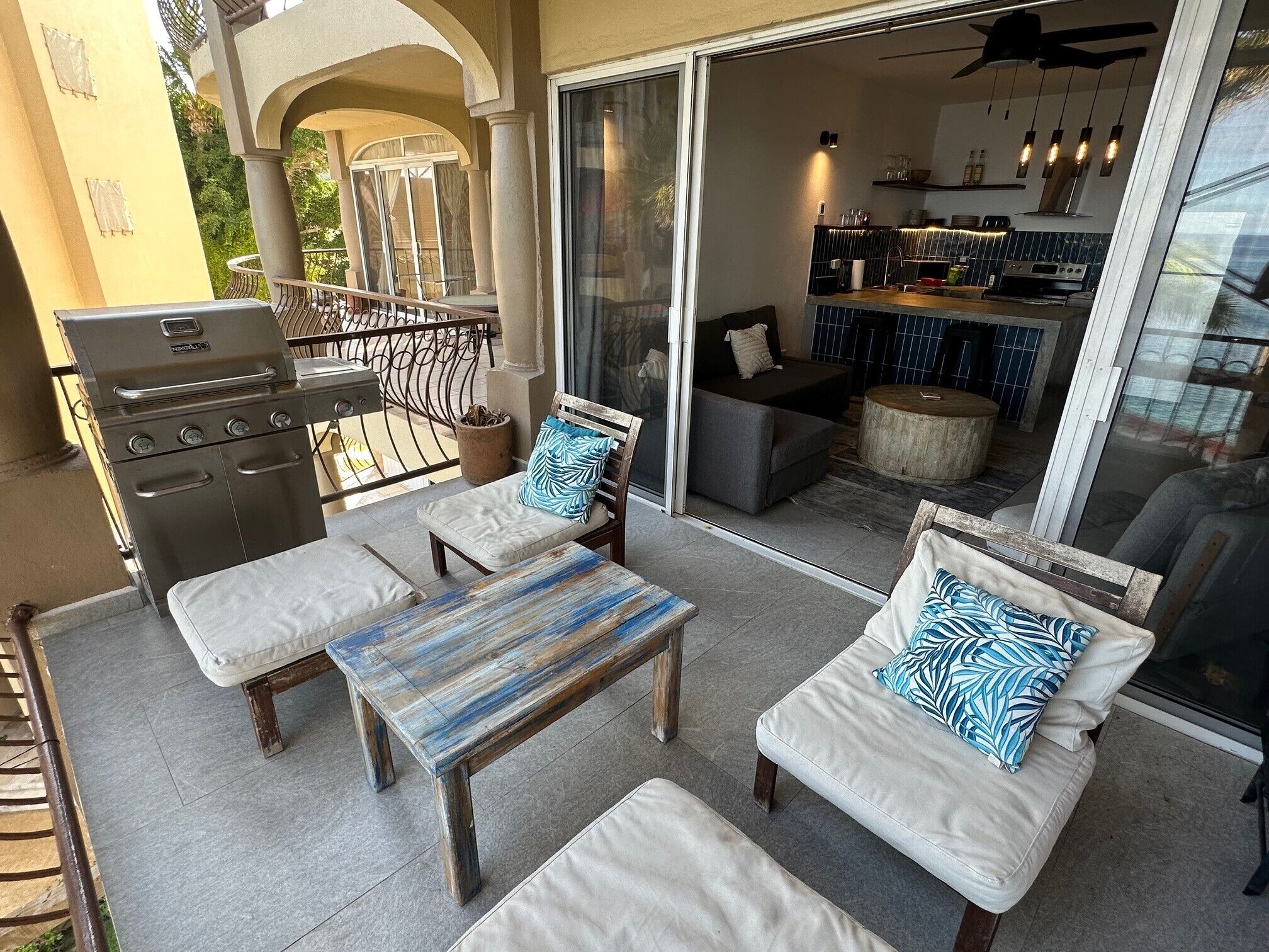 An outdoor patio with a grill, seating area, and a view into the house.