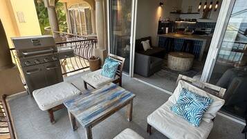 An outdoor patio with a grill, seating area, and a view into the house.