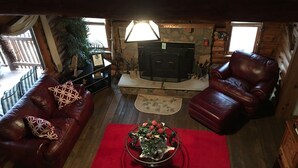 A cozy living room with two leather sofas, a fireplace, and a coffee table with flowers. - Authentic Log cabin with something for everyone! (Marthasville)