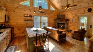 A log cabin interior with a kitchen, dining area, and living room.