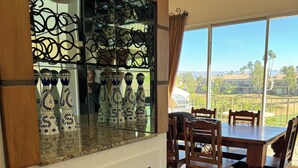 A dining area with a table and chairs, a glass-top table, and a view of the outdoors. - PGA West La Quinta STR #068246 - Close to Golf, Tennis & Music Festivals (La Quinta)