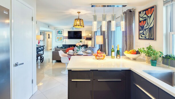 Una cocina moderna con una isla central, electrodomésticos de acero inoxidable y un comedor con sofá y mesa.
