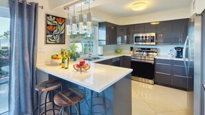 Una cocina moderna con una isla central, electrodomésticos de acero inoxidable y un ventanal amplio.