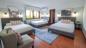 Ein Schlafzimmer mit zwei Betten, einem Schlafsofa und einem Fenster mit Blick auf Grünflächen.