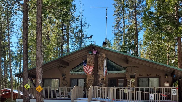 A lodge with a stone facade, a wooden deck, and an American flag.