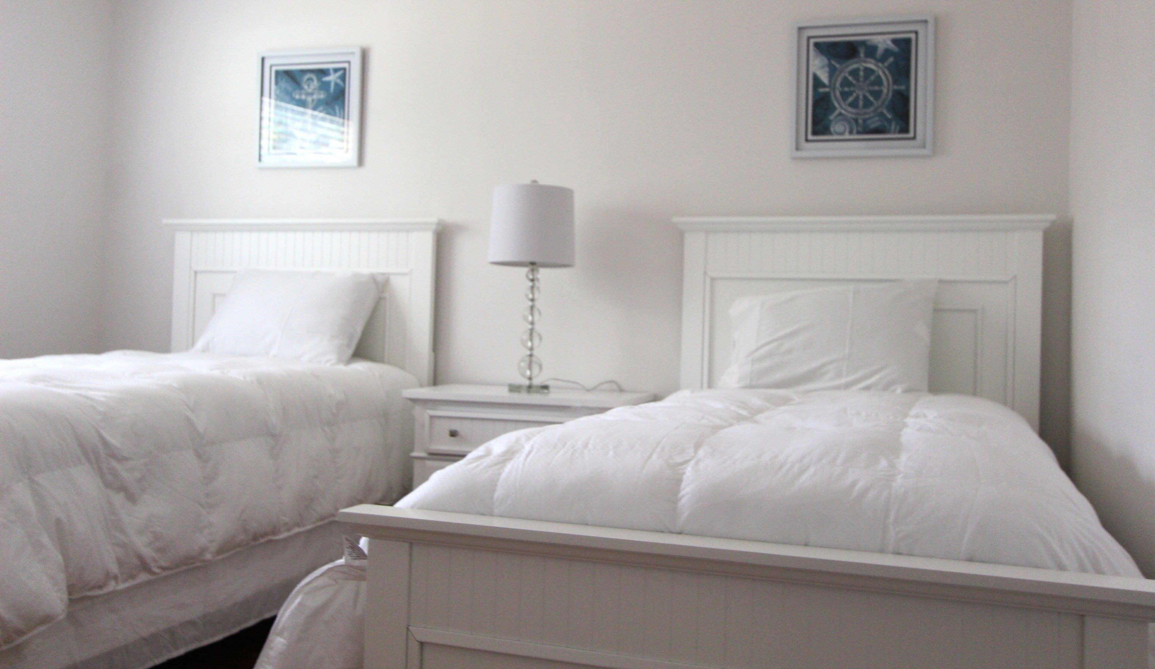 Une chambre avec deux lits, une table de chevet et une lampe fixée au mur.