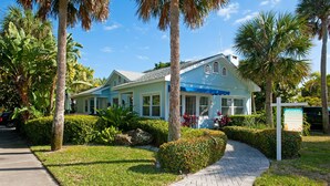 A light blue building with a blue awning, surrounded by palm trees and well-maintained landscaping. - Beautiful Clearwater Beach Home just across from the Beach - Drive to your door. (Clearwater Beach)