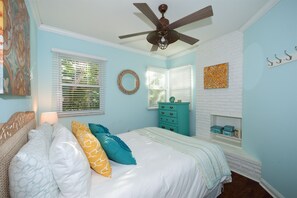 Une chambre à coucher avec un lit, une commode, un ventilateur de plafond et une cheminée.