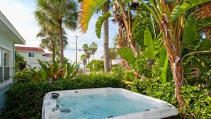 A hot tub surrounded by lush greenery and a residential building in the background. - Beautiful Clearwater Beach Home just across from the Beach - Drive to your door. (Clearwater Beach)