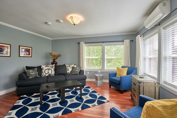 A living room with a gray sofa, a blue armchair, a coffee table, and a patterned rug.