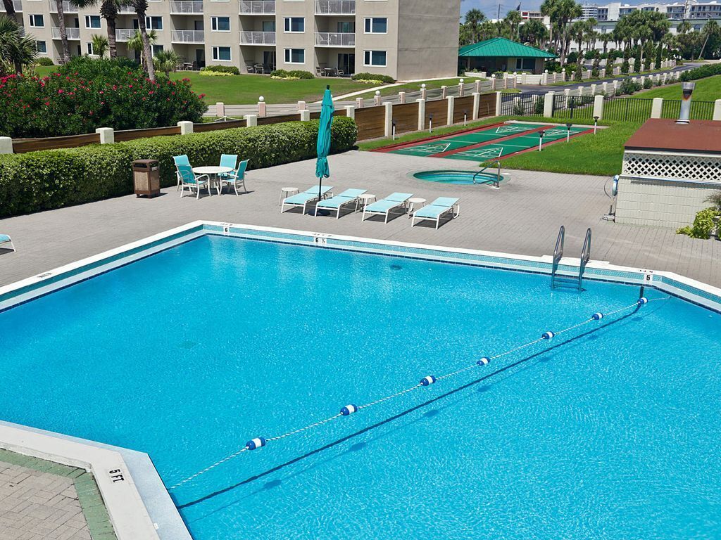 A swimming pool with lounge chairs and a small garden area.