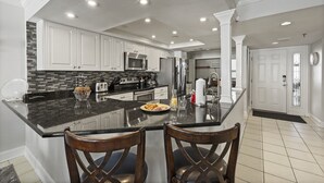 A modern kitchen with white cabinets, granite countertops, and stainless steel appliances.