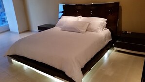 Une chambre à coucher moderne, dotée d’un grand lit, de deux tables de chevet et offrant une vue sur l’extérieur grâce à une fenêtre.
