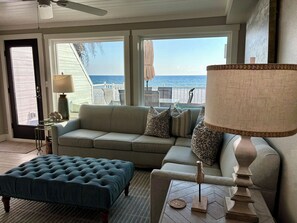 Relax in this serene space with a comfortable sofa, tufted ottoman, and ocean views from the large window.