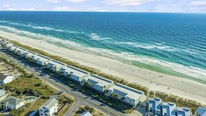 Un hotel costero con vista a la playa, con filas de habitaciones y una carretera paralela a la orilla.