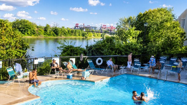A swimming pool with lounge chairs, a view of a lake, and a bridge in the background. - Riverfront Downtown Nashville (nashville)