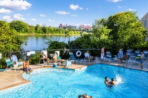 A swimming pool with lounge chairs, a view of a lake, and a bridge in the background.