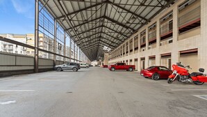 A covered parking area with multiple cars and a motorcycle, large windows, and a high ceiling. - Riverfront Downtown Nashville (nashville)