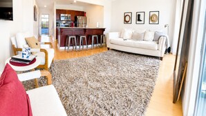 A living room with a sofa, a coffee table, a rug, a kitchen area with a bar, and framed pictures on the wall. - Riverfront Downtown Nashville (nashville)