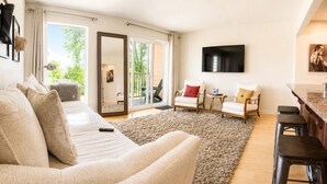 A living room with a sofa, chairs, a TV, and a large window. - Riverfront Downtown Nashville (nashville)