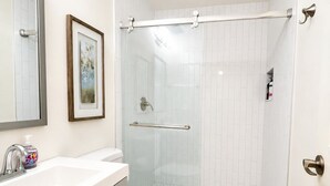 A bathroom with a white sink, toilet, and shower with glass doors. - Riverfront Downtown Nashville (nashville)