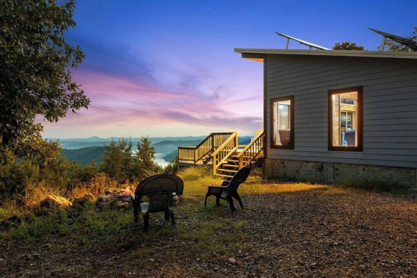 A cabin with a wooden deck and a view of the mountains.
