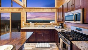 Una cocina moderna con armarios de madera, un ventanal con vistas panorámicas, un microondas integrado y una cocina a gas.
