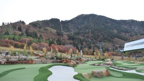 A golf course with a water hazard, rocky terrain, and a mountainous backdrop.