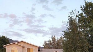 A two-story house with a garage, a well-maintained lawn, and a large tree in the front yard.