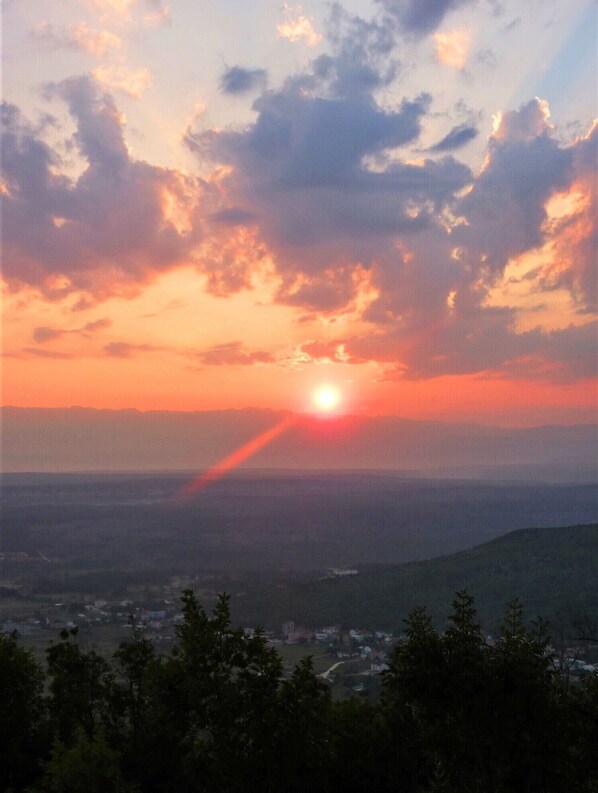 A sunset over a mountainous landscape with a town below.