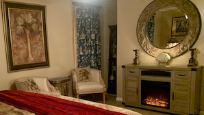 Une chambre à coucher avec un lit, une cheminée, un miroir et une chaise.