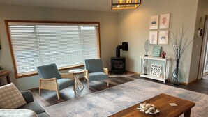 A cozy living room with a sofa, two armchairs, a coffee table, and a fireplace.