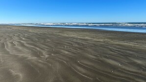 A wide sandy beach with gentle waves and a clear blue sky.