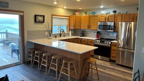 A modern kitchen with wooden cabinets, stainless steel appliances, and a large island with stools.