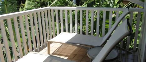 Un balcon avec une balustrade blanche, une petite table et une chaise.