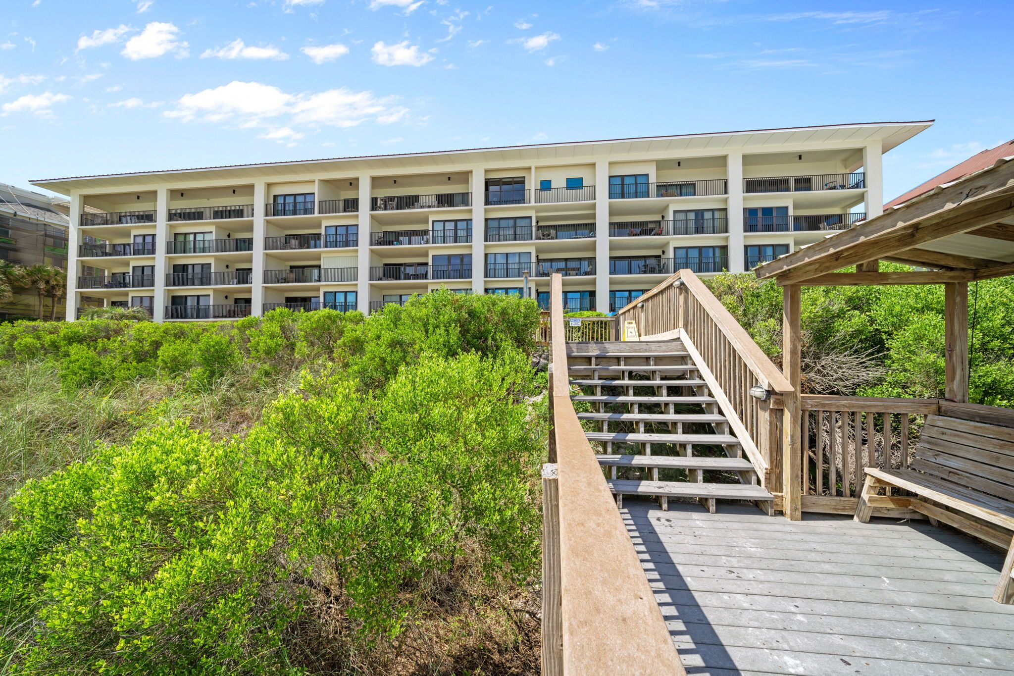 Un hotel de varios pisos con balcones, una escalera de madera y un área exterior techada.