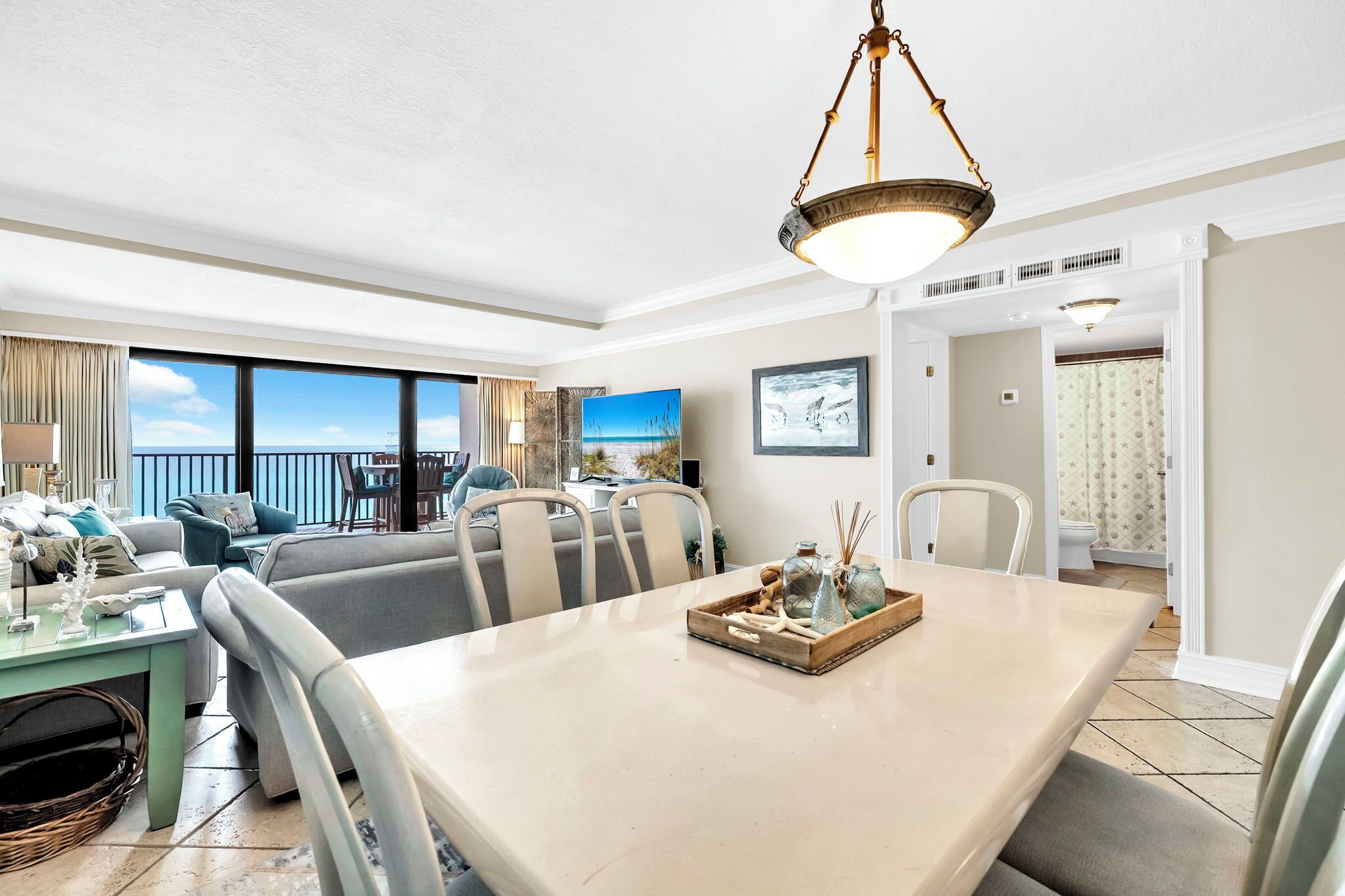 A spacious living area with a dining table, chairs, and a view of the ocean.