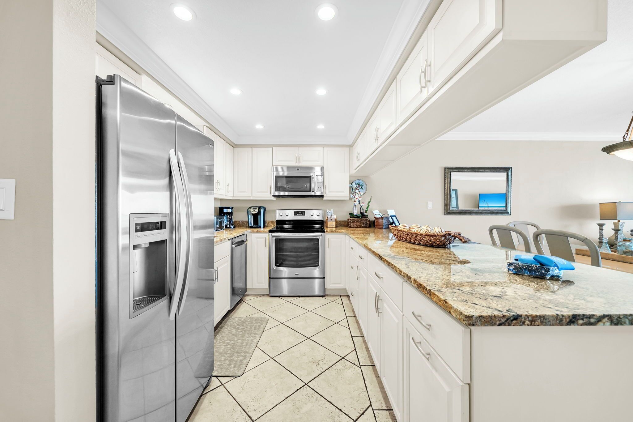 A modern kitchen with stainless steel appliances, white cabinetry, and a granite countertop.