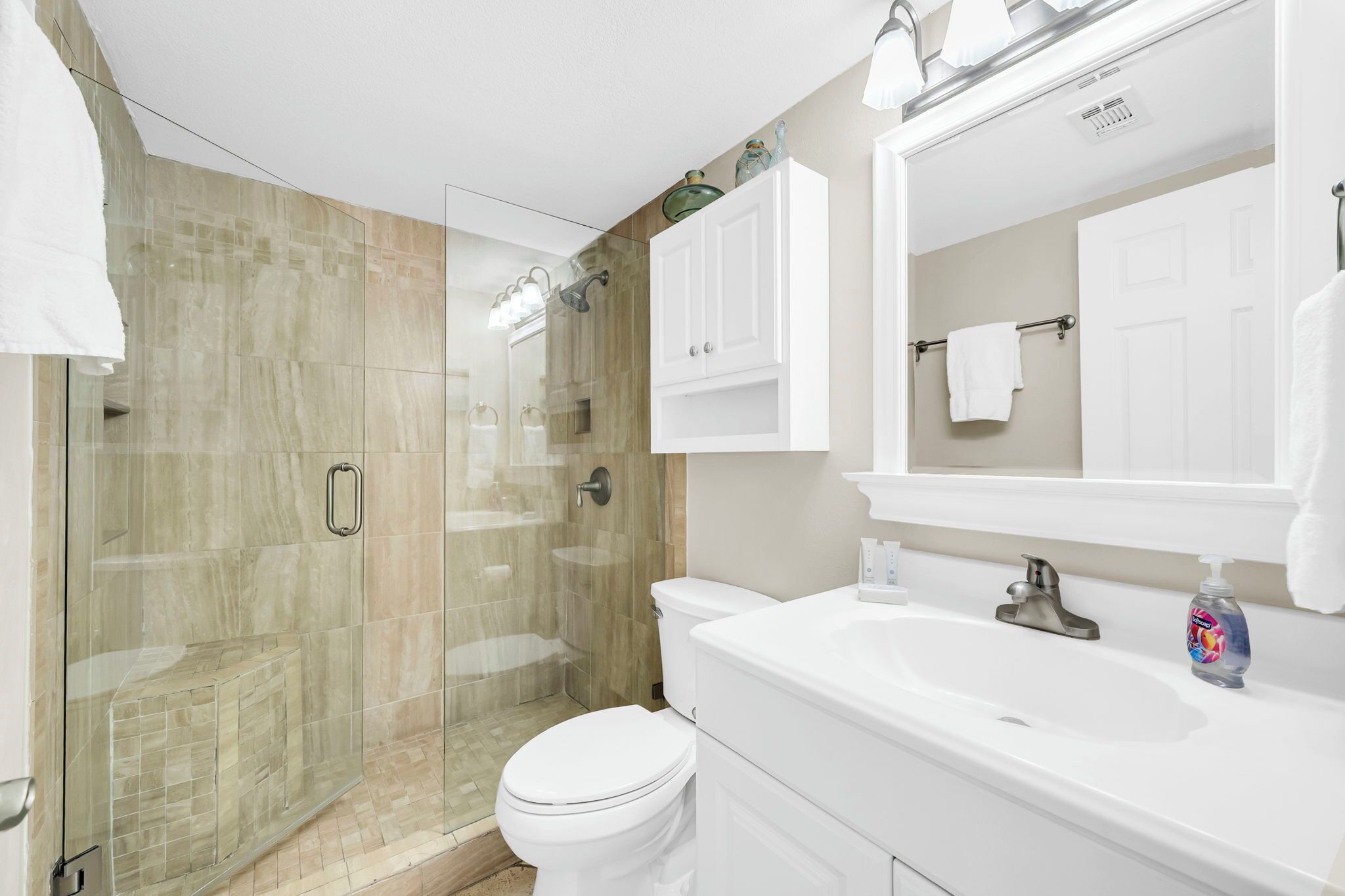 Un bagno moderno con doccia a vetro, un water bianco e un mobile lavabo con lavandino e specchio.
