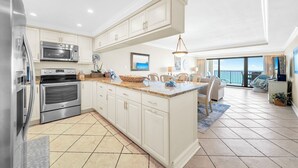 Une cuisine moderne avec des meubles blancs, des appareils en acier inoxydable et un grand îlot central.