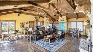 A spacious living area with a high ceiling, wooden beams, and a chandelier. A dining area with a table and chairs is visible. - SkyHouse cabin on the West Rim (Canyon)