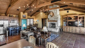 A spacious living area with a stone fireplace, wooden beams, and a stone wall. - SkyHouse cabin on the West Rim (Canyon)