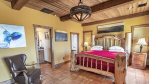 A bedroom with a wooden bed, a chair, and artwork on the walls. - SkyHouse cabin on the West Rim (Canyon)