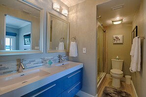 A bathroom with a double sink, a large mirror, and a shower area.
