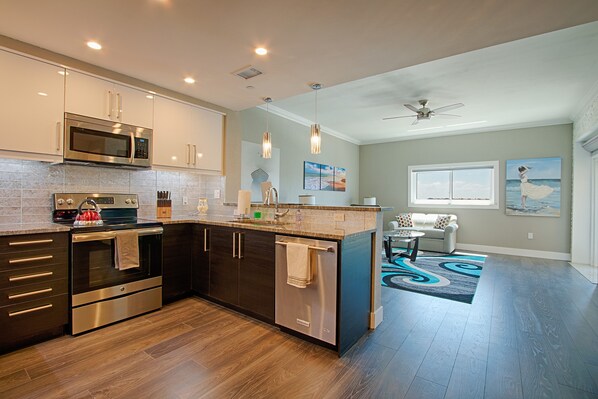 A modern kitchen with stainless steel appliances, a dishwasher, and a dining area with a view of the outdoors.