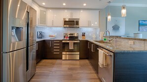 Una cocina moderna con electrodomésticos de acero inoxidable, armarios blancos y encimera de granito.